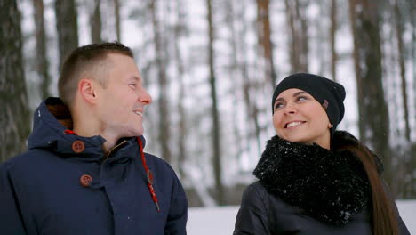 Close-up-of-a-man-and-a-woman-in-love-standing-in-the-winter-forest-hugging-each-other-and-looking-into-the-distance